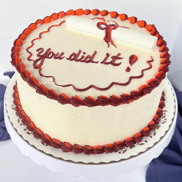 Round graduation cake with red diploma and piping